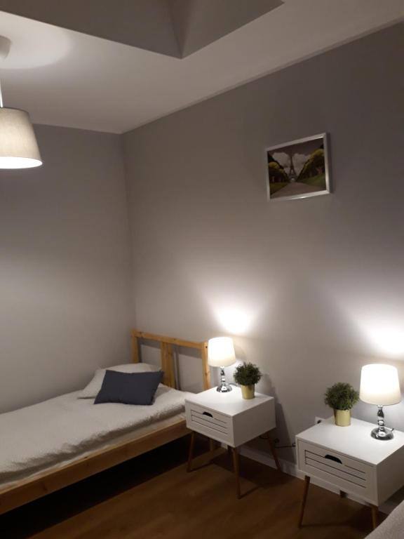 Pokój z pojedynczym łóżkiem i szafkami nocnymi w Arkadia Hostel w Mławie